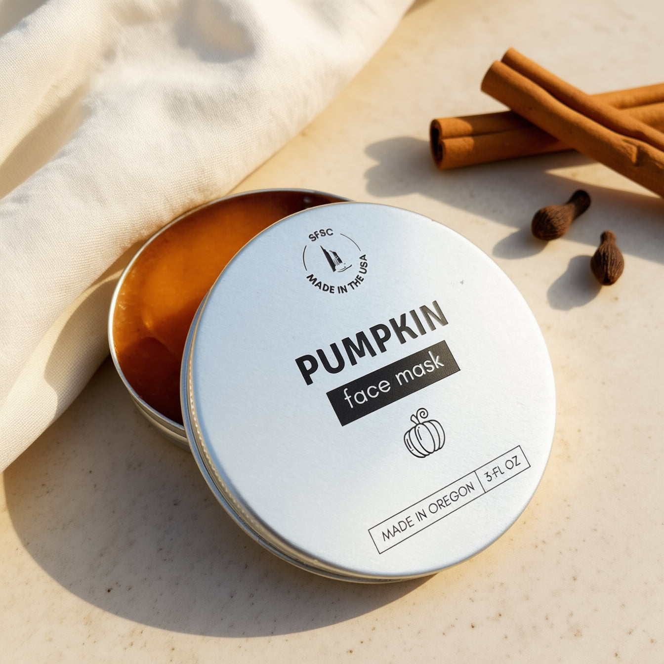 Pumpkin face mask in a tin with cinnamon sticks on a light background